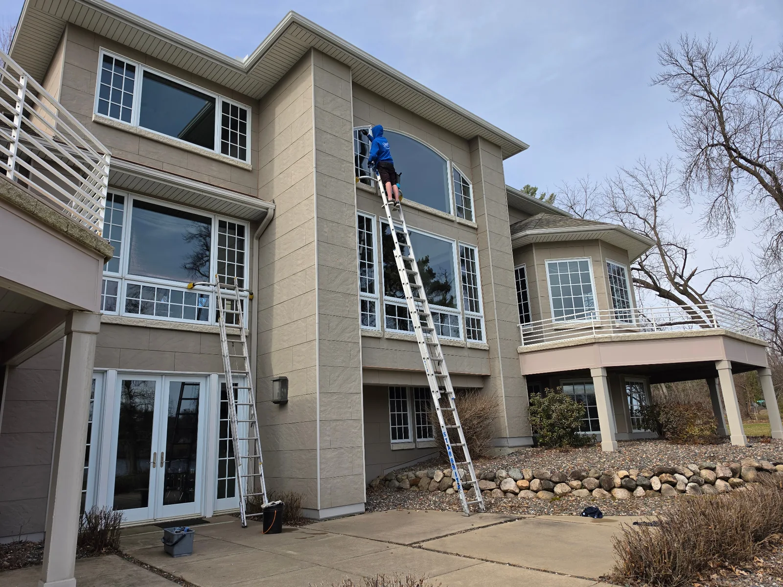 Starbrite technician on a ladder cleaning a large residential window