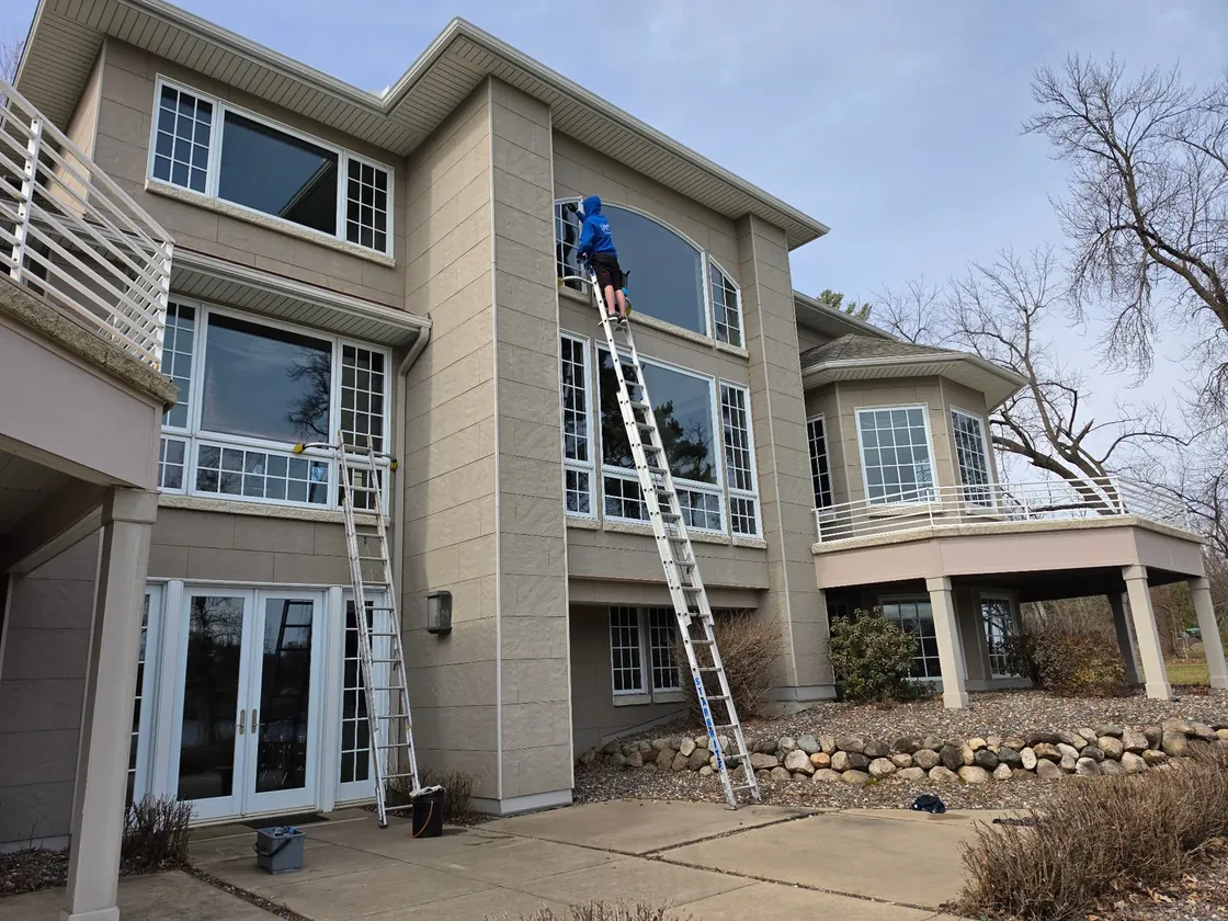 Starbrite technician on a ladder cleaning a large residential window